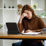 Asian women sitting in a home office With stress and eye strain.stressed reviewing contract